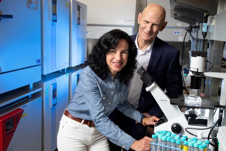 A woman and man standing near a microscope.